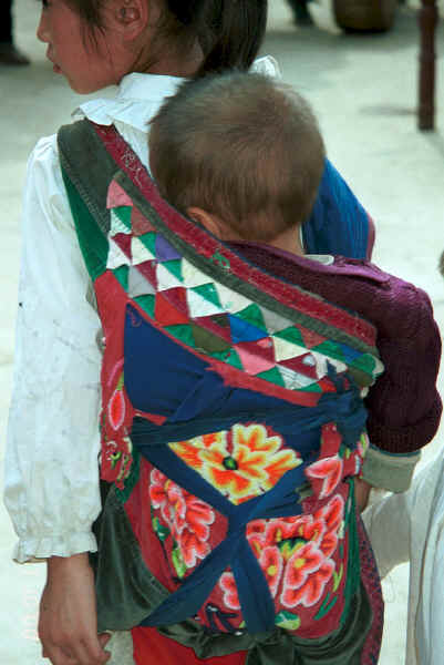 A baby carrier bought in the market but with an added patchwork band on the top - Sha Jiao village, Wan Teng township, Xingyi metropolitan area, Guizhou province 0010m17.jpg