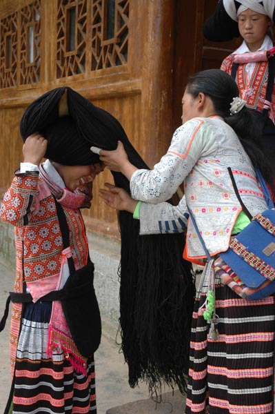 Jpeg 61K Dressing the hair of a Long Horned Miao girl in festival dress by winding the girl's own hair, wool and perhaps inherited hair around the wooden 'horn'.