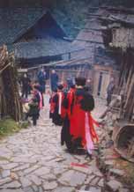 to Jpeg 57K e30e 25 February 2004, the fourth day of the festival, in Langde village, Guizhou province, On this day, the ceremony was to take the spirit of the mountain dragon inside each home to live there so the family would enjoy good fortune in the future. The shaman and a group of men all wore traditional dress. These men were the leading people of the ceremony and of the community. They must be well thought of by the villagers before they can be selected as participants or else they cannot play the roles. When the ceremony started, the shaman went in front leading the way to each home. On entering each family's house they were offered cups of rice wine by the head of the family and fire crackers were also set off. While in the house, they played lusheng and danced in a circle to the rhythm of the bronze drum. When leaving the house, the owner gave them some red ribbons and cigarettes. 