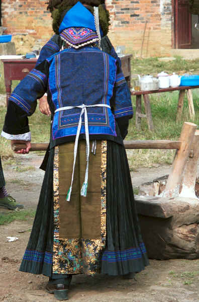 Back view of Black Miao woman wearing her festival finery kneading festival sticky rice, Zuo Qi village, Min Gu township, Zhenfeng county, Guizhou province 0010q05.jpg