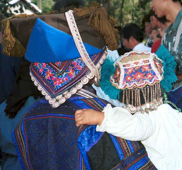 Back view of mother and child showing their embroidered headdresses and the beautifully embroidered back panel of the mother's jack - Zuo Qi village, Min Gu township, Zhenfeng county, Guizhou province 0010q26.jpg