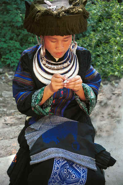 Black Miao girl in her festival finery demonstrating her embroidery on a baby carrier piece - Zuo Qi village, Min Gu township, Zhenfeng county, Guizhou province 0010q34A.jpg