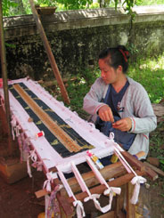 81K Jpg - On the grounds of one of the wats In Luang Prabang, Laos, we bought cold drinks from a woman manning a small stall. Excitingly, she was couching golden threads on a small piece of cloth! It was nice to see people still doing this in a serene open atmosphere and not in a sweatshop. She didn’t speak any English so unfortunately I don’t know if this was an item to be sold later or for her own use. I did compensate her for taking photos!