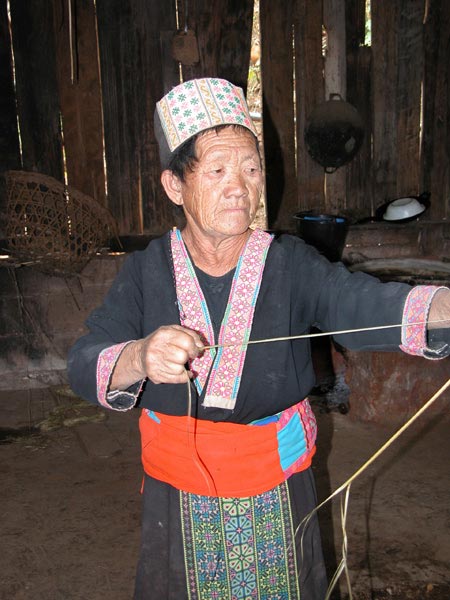 Jpeg 56K An old White Hmong woman stripping hemp from under the bark in the village of Ban Pha-nok-kok 3425