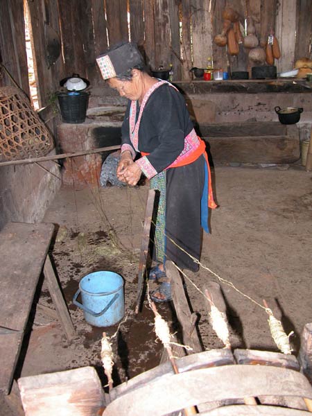 Jpeg 56K A White Hmong woman splicing one of the hemp threads which are about to be spun together in the village of Ban Pha-nok-kok  3426