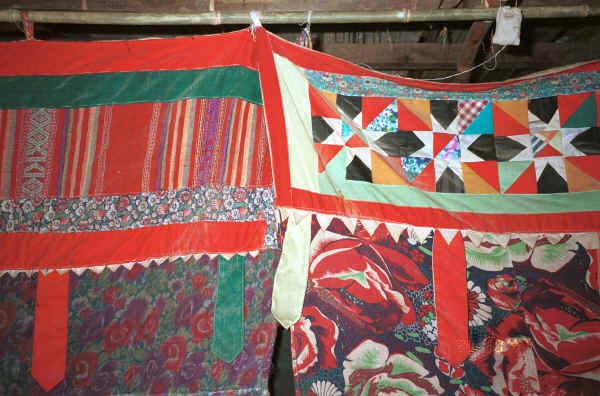 Jpeg 46K Decorative headings to curtains separating sleeping from living areas in a Black Thai house. Note the woven fabric in the heading to the left and pieced work in the heading to the right. The hanging tabs echo those on some of the baby carriers in the area. Dien Bien Phu, Lai Chau Province October 1995.