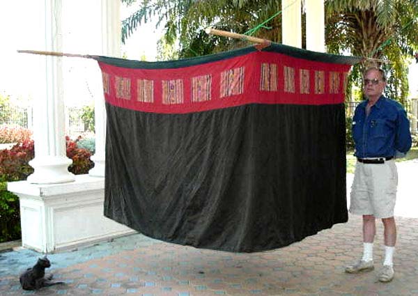 Jpeg 43K Lao-Tai (possibly Black Thai (Tai Dam) style) complete mosquito net illustrating how it would be hung over bamboo poles. The top is plain white cotton cloth, possibly hand woven and spun, not netting. Note the size against a 6' man.