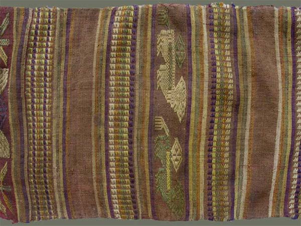 Jpeg 58K From Xam Tai, detail of an unusual mosquito net border (now in the collection of Pamela Cross) which is a lovely shade of brown, with accents of purple, gold and yellow. It is unusual because of the design motifs: elongated, stylized star motifs with arrows; also present in a few places are stylized animal motifs and figures with up-raised hands. One end is a dark red rather than brown. It is all handspun cotton (or perhaps fine hemp?) with cotton and some silk supplementary weft. Condition is very good, tho there are soiled areas throughout. Size: 274" (22'-10") x 9.5"