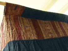 to Jpeg 54K Top corner detail of Tai Daeng Mosquito Net (pha mung) from Xam Tai in northeast Laos. Approximately: 61" x 65" on the sides and 60" high; hanging pockets extends 4" from main 'box'. Four panels on each side of handspun, handwoven indigo cotton, with silk and cotton heading border in good condition; top of four panels (one is pieced making three parts) gold-colored handspun, handwoven cotton. One side (side 'd') has a panel replaced, or of darker color indigo. Several patches and some holes, although none are larger than 1". A few patches of supplementary warp scraps. All handstitched. Early 20th century.