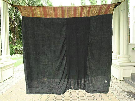 50K Jpeg Tai Daeng Mosquito Net (pha mung) from Xam Tai in northeast Laos. Approximately: 61" x 65" on the sides and 60" high; hanging pockets extends 4" from main 'box'. Four panels on each side of handspun, handwoven indigo cotton, with silk and cotton heading border in good condition; top of four panels (one is pieced making three parts) gold-colored handspun, handwoven cotton. One side (side 'd') has a panel replaced, or of darker color indigo. Several patches and some holes, although none are larger than 1". A few patches of supplementary warp scraps. All handstitched. Early 20th century.