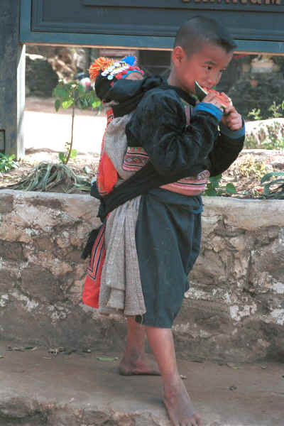 Blue Hmong boy carrying a baby in a baby-carrier on his back in a village on Doi Suthep 8812l01.jpg (363840 bytes)