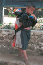 to Jpeg 29K Blue Hmong boy carrying a baby in a baby-carrier on his back in a village on Doi Suthep 8812l01