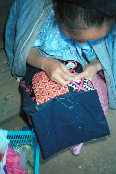 Blue Hmong woman sewing on applique possibly to a young man's jacket 8812l14