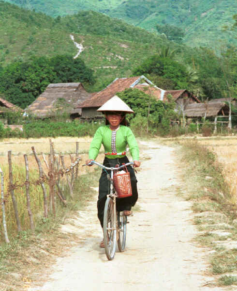 Jpeg 41K Black Thai young woman cycling out of her village wearing a straw hat over her head dress to give added protection from the sun.  Dien Bien Phu, Lai Chau Province. 9510D36.JPG