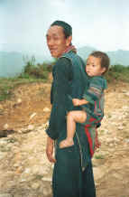 to Jpeg 30K Black Hmong man with a young girl - probably his granddaughter - in a baby carrier on his back, in the hills around Sa Pa, Lao Cai Province.  9510I28.JPG