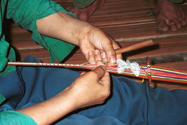 Jpeg 34K 9511A04 Weaving a braid with the warp tension achieved between toes and a tie around the waist. Although the braid is narrow quite a complicated shed is set up. Luong village on the road from Sa Pa to Lao Cai town, Lao Cai province.