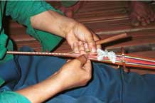 to Jpeg 34K 9511A04 Weaving a braid with the warp tension achieved between toes and a tie around the waist. Although the braid is narrow quite a complicated shed is set up. Luong village on the road from Sa Pa to Lao Cai town, Lao Cai province.