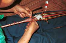 Jpeg 41K 9511A05 Weaving a braid with the warp tension achieved between toes and a tie around the waist. Although the braid is narrow quite a complicated shed is set up. Luong village on the road from Sa Pa to Lao Cai town, Lao Cai province.