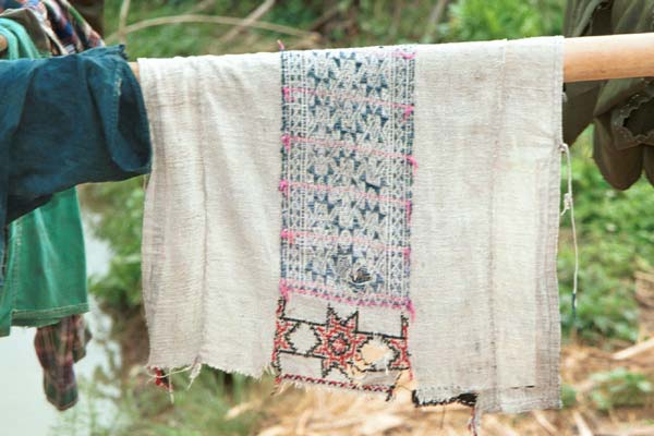 Jpeg 39K 9511A11 Dao Quan Trang woman's bodice hanging out to dry and showing the reverse side of the embroidery with the characteristic stars at the base. The background fabric appears to be hand spun and woven and is probably cottton. Luong village on the road from Sa Pa to Lao Cai town, Lao Cai province.