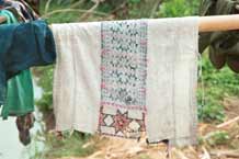 to Jpeg 39K 9511A11 Dao Quan Trang woman's bodice hanging out to dry and showing the reverse side of the embroidery with the characteristic stars at the base. The background fabric appears to be hand spun and woven and is probably cottton. Luong village on the road from Sa Pa to Lao Cai town, Lao Cai province.